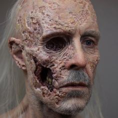 an older man with white hair and facial markings on his face is covered in dirt