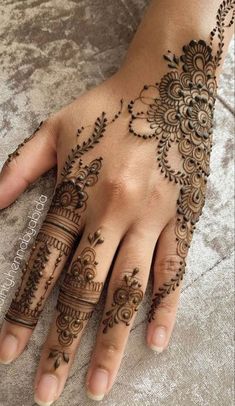 a woman's hand with henna tattoos on it