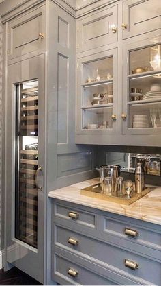 a kitchen with gray cabinets and gold pulls on the door knobs is seen in this image