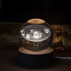 a glass ball with an image of the solar system in it on top of a wooden stand