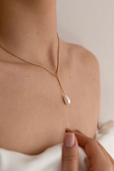 The Marilyn Pearl Necklace is handcrafted with a 14k gold-filled 45cm wheat chain and a single drop pearl dangling from a 1 inch chain (both customizable to your desired length, please leave a note if desired). Packaged in an elegant plastic-free reusable jewelry box, this necklace makes the perfect gift or special treat for oneself.   *14k gold-filled wheat chain *Freshwater drop pearl *Hypoallergenic, suitable for even the most sensitive skin *Delivered in a 100% silk jewelry pouchette inside a gift box *Sustainable magnetic closure jewelry box and customizable card Please note, as we use only natural pearls, shape and size may vary slightly.  We offer a one year guarantee from the date of delivery. Pearl Necklace Outfit, Simple Pearl Necklace, Single Pearl Necklace, Garnet Heart, Pretty Jewelry Necklaces, Necklace Outfit, Silk Jewelry, Bridal Pearl Necklace, Pearl Chain Necklace