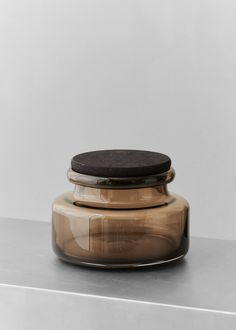 a glass jar sitting on top of a metal counter next to a black object in the middle