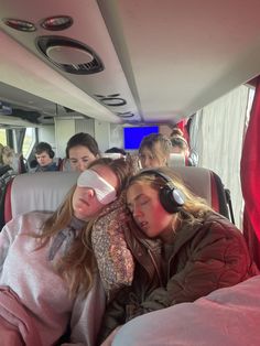 three girls are sleeping on a bus with headphones in their ears and one girl has her eyes closed