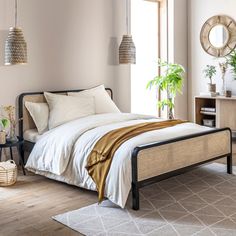 a bed sitting in a bedroom next to a wooden dresser and window with potted plants on it