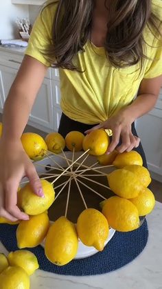 a woman arranging lemons on top of a table