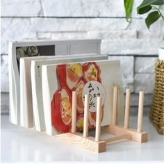 a wooden book stand with four books on it and a potted plant in the background