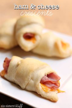 two pastries on a white plate with ham and cheese in the middle one is cut in half