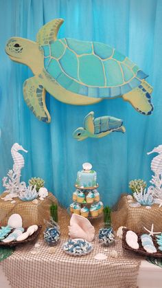 a table topped with cakes and plates covered in sea animals next to a giant turtle