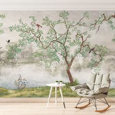 a room with a chair, table and painting on the wall that has birds flying over it