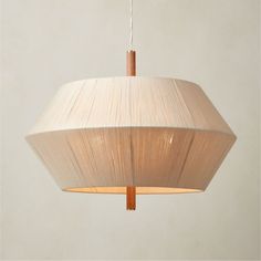 a white lamp hanging from a ceiling with a wooden stick sticking out of it's center