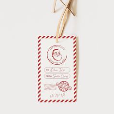 a pair of scissors hanging from a red and white tag with a santa stamp on it