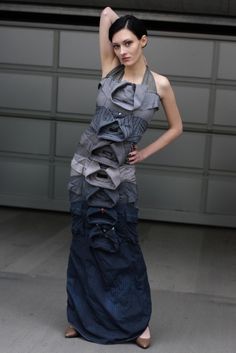 a woman standing in front of a garage door wearing a dress made out of clothes