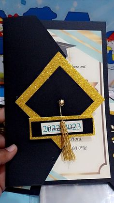 a graduation cap and tassel is being held by someone's hand in front of some other items