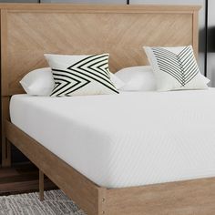 a bed with white pillows and wooden headboard