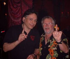 two men standing next to each other giving the peace sign