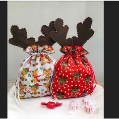 two bags with reindeer heads on them sitting next to candy