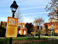 a sign that reads 50 year women in math sits on the grass next to a lamp post