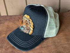 Transform your look with our Golden Trucker Hat. This versatile hat is great for music festivals, outdoor activities, and more. Channel your inner rocker and country music aficionado while staying comfortable and stylish in western fashion. It features a classic chino twill front panel and a soft tea stain mesh back panel. The antique silver Southwestern-inspired Concho with faux turquoise adds a touch of rustic charm. With a velcro closure and a comfort sweatband, it's perfect for all head sizes. Casual Hats For Country Events, One Size Fits Most, Casual Hat Bands For Rodeo, Outdoor Trucker Hat With Brim, Casual Short Brim Festival Hats, Casual Cap For Country Events, Western Style Trucker Hat With Short Brim For Festivals, Western Style Trucker Hat For Summer Outdoor, Adjustable Country Style Trucker Hat For Outdoor, Casual Black Hat Band For Festivals