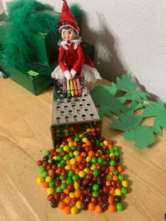 an elf is sitting on top of a box filled with candy