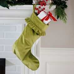 a christmas stocking hanging from a fireplace with presents in it and greenery on the mantle