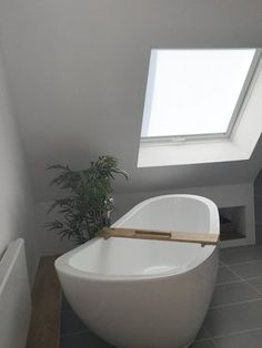 a white bath tub sitting under a skylight in a bathroom