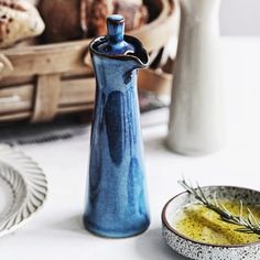 a blue vase sitting on top of a table next to a white plate and bowl