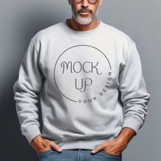 a man with glasses standing in front of a gray wall wearing a sweatshirt that reads mock up your bed