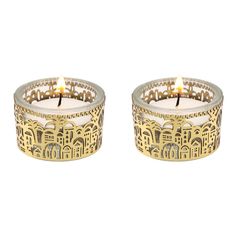 two small candles sitting next to each other on a white surface with gold trimmings