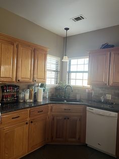 a kitchen with wooden cabinets and black counter tops, along with a white dishwasher