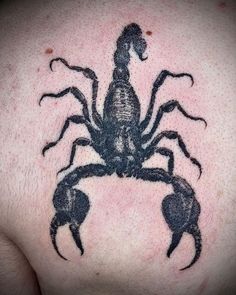 a black scorpion tattoo on the back of a man's shoulder