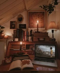 a laptop computer sitting on top of a wooden desk next to a book and candle