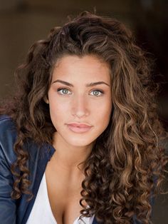 a beautiful young woman with curly hair and blue eyes posing for a photo in a leather jacket