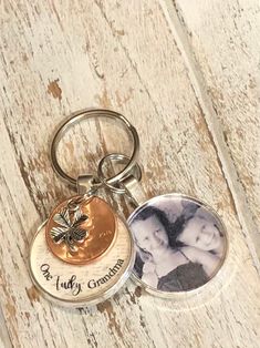 two personalized keychains on a wooden surface, one has a photo and the other has a butterfly