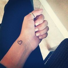 a person with a small heart tattoo on their wrist