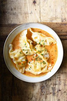 a white bowl filled with dumplings on top of a wooden table