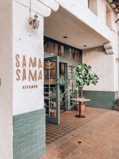 the outside of a restaurant with potted plants on the patio and signage for samma kitchen