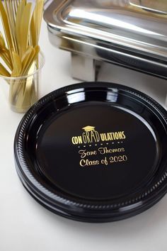 a black plate with gold lettering on it next to silver trays and utensils