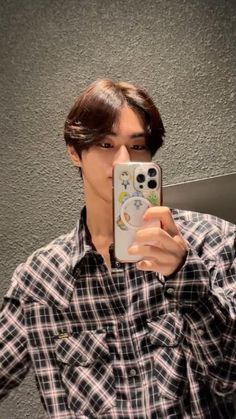 a young man taking a selfie in front of a mirror with his cell phone