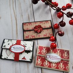 three christmas cards on a white wooden table with red berries and holly berry tree branches