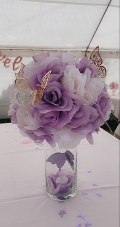 a vase filled with purple flowers on top of a white table cloth covered tablecloth