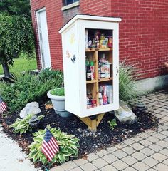 a small white cabinet sitting in the middle of a garden