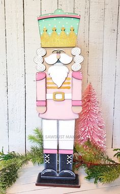 a wooden nutcracker with a crown on it's head standing in front of a christmas tree