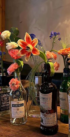 several bottles with flowers in them sitting on a table next to other bottles and vases