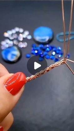 a person holding a piece of wire with beads on it and another item in the background