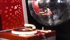 an old record player sitting on top of a suitcase in front of a disco ball