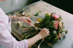 a woman cutting flowers with scissors on a wooden table