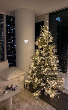 a living room with a christmas tree in the corner and a window overlooking the city