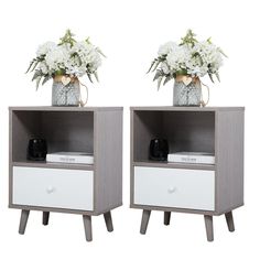 two nightstands with flowers in vases on top of each one, both side by side