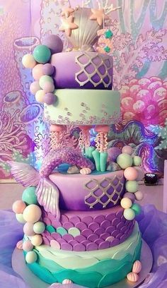 a three tiered cake with mermaid decorations on it