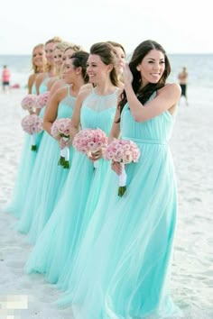 a group of women standing on top of a beach next to each other holding bouquets